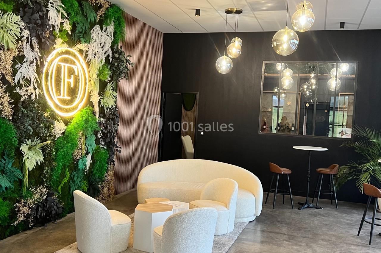 Espace lounge moderne avec mobilier blanc, mur végétal éclairé et luminaires suspendus dans un intérieur design.