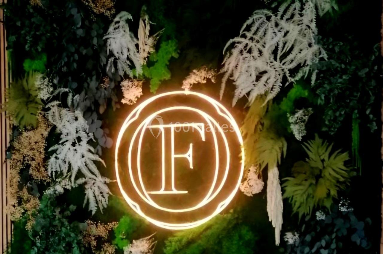 Mur végétal décoratif avec un logo lumineux en forme de cercle contenant la lettre ’F’.