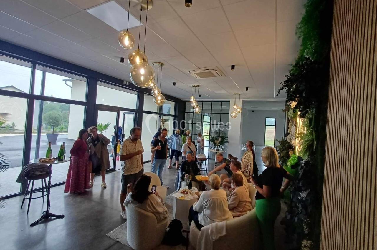 Un groupe de personnes échange dans un espace moderne et lumineux avec des baies vitrées et une décoration végétale.