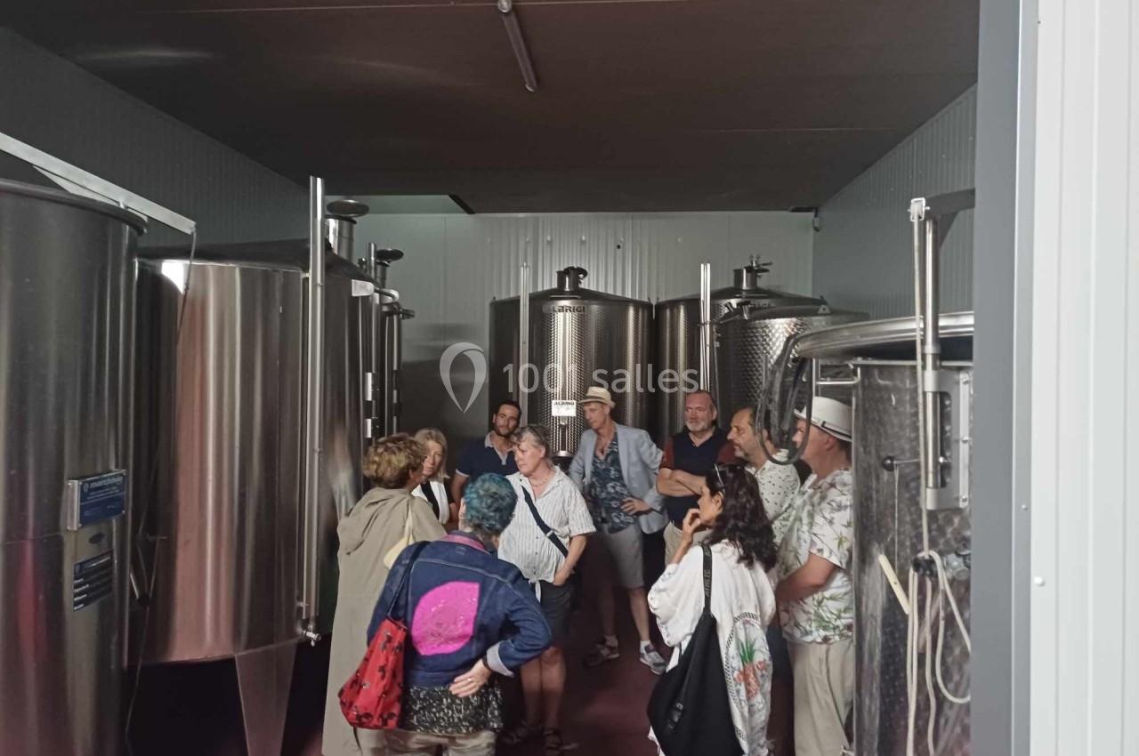 Un groupe de personnes visite une salle avec des cuves métalliques dans un environnement industriel.