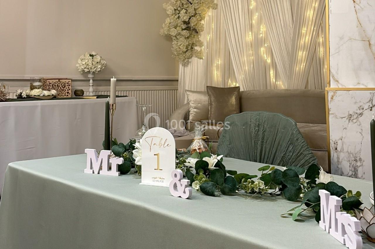 Table décorée pour un mariage avec guirlande lumineuse, feuillage, bougies et panneau indiquant ’Table 1’.