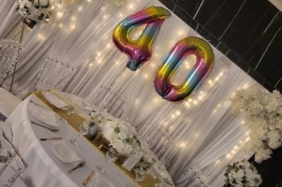 Mur décoratif sur le thème des années 90 avec graffitis colorés, ballons blancs et dorés, et accessoires rétro.