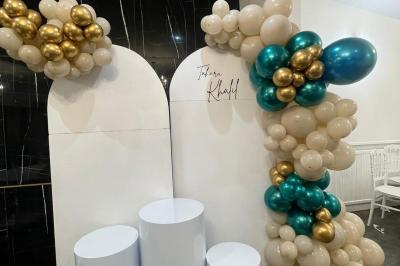 Mur décoratif sur le thème des années 90 avec graffitis colorés, ballons blancs et dorés, et accessoires rétro.