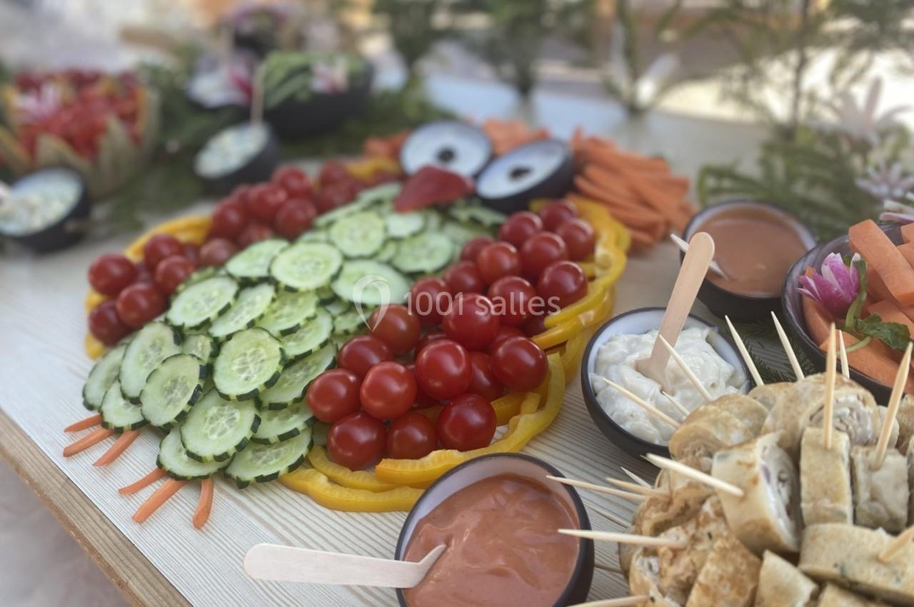 Plateau de légumes en forme de hibou avec concombres, tomates cerises, poivrons et sauces en accompagnement.