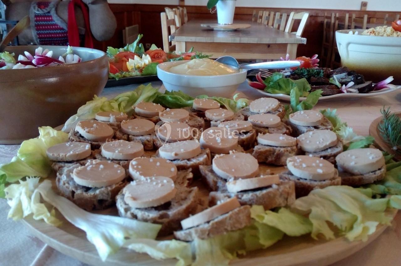 Plateau de toasts au foie gras disposés sur un lit de salade, entouré de divers plats sur une table en bois.