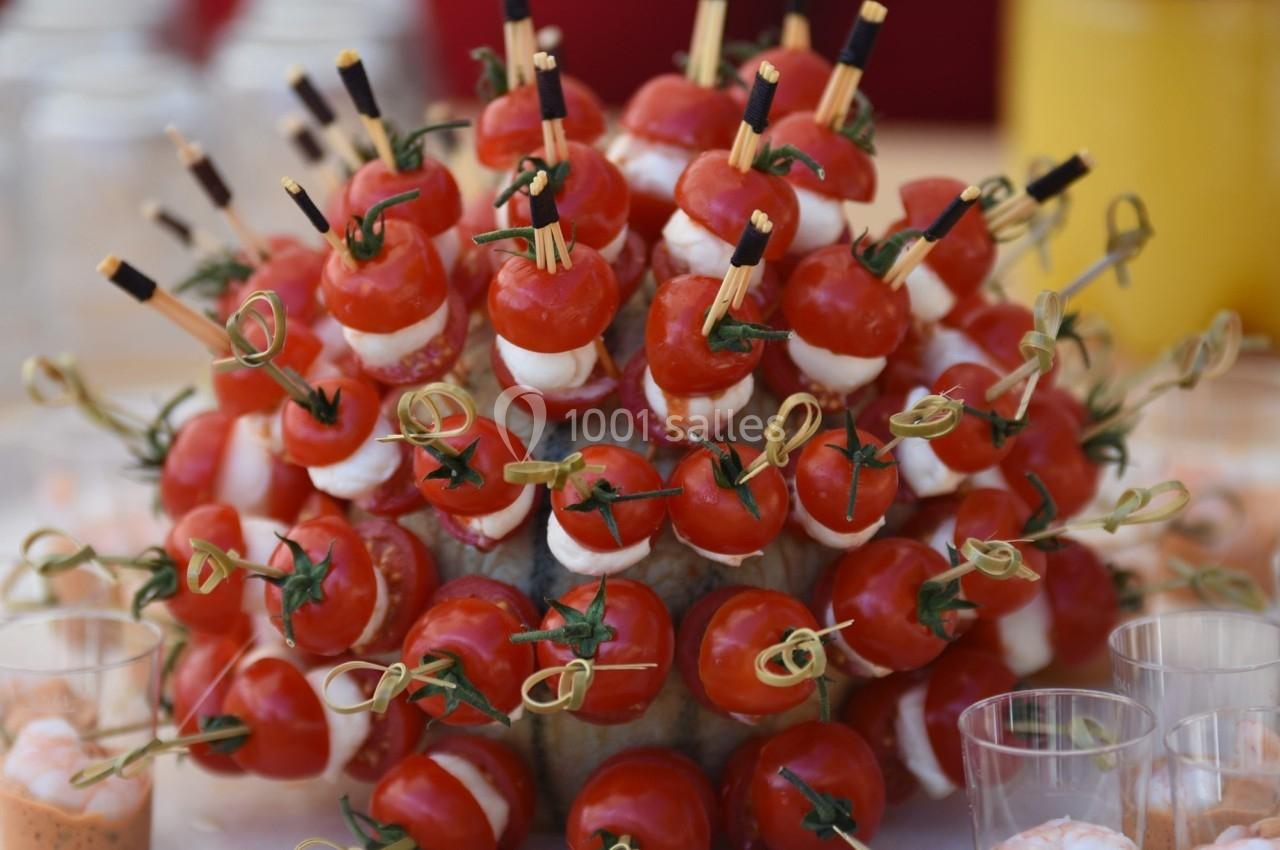 Bouquet de brochettes apéritives avec tomates cerises, mozzarella et jambon disposé sur un support rond.