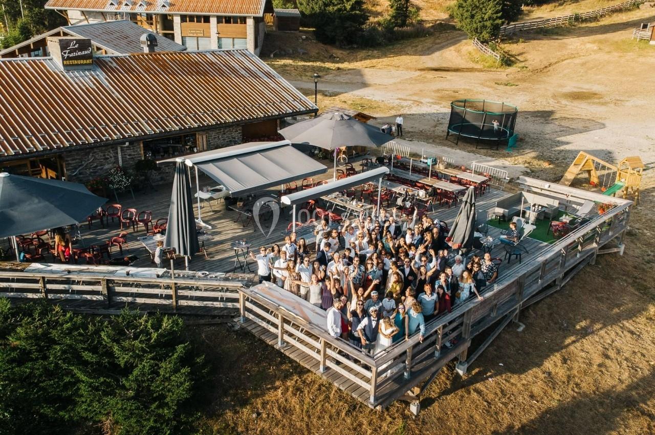 Groupe de personnes rassemblées sur une terrasse en bois près d'un bâtiment dans un cadre rural ensoleillé.