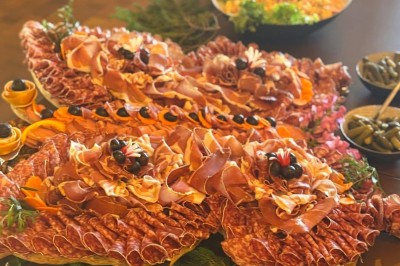 Plateau en bois garni de macarons colorés, tartelettes aux fruits et pâtisseries variées disposés en rangées.