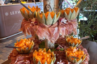Plateau en bois garni de macarons colorés, tartelettes aux fruits et pâtisseries variées disposés en rangées.