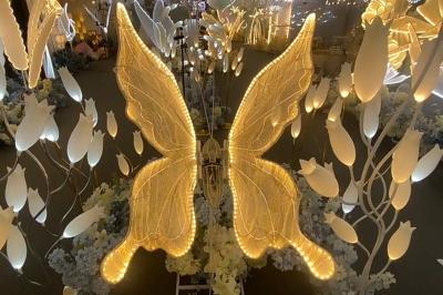 Un anneau lumineux sur trépied et un panneau noir avec un logo doré ’IM Events’ devant un rideau coloré.