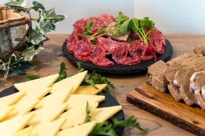 Chambre d'hôtel lumineuse avec lit double, coin salon, rideaux jaunes, mobilier en bois et fauteuils bleus.
