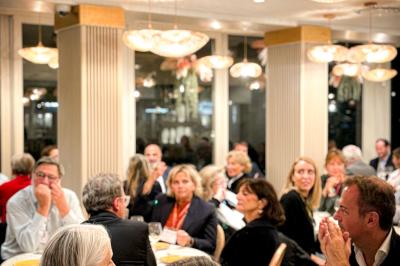 Des personnes dînent et discutent dans un restaurant lumineux à la décoration moderne et chaleureuse.