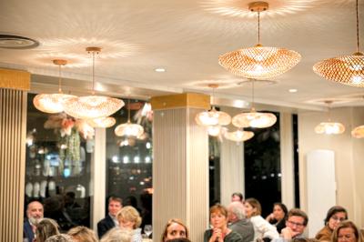 Des personnes dînent et discutent dans un restaurant lumineux à la décoration moderne et chaleureuse.