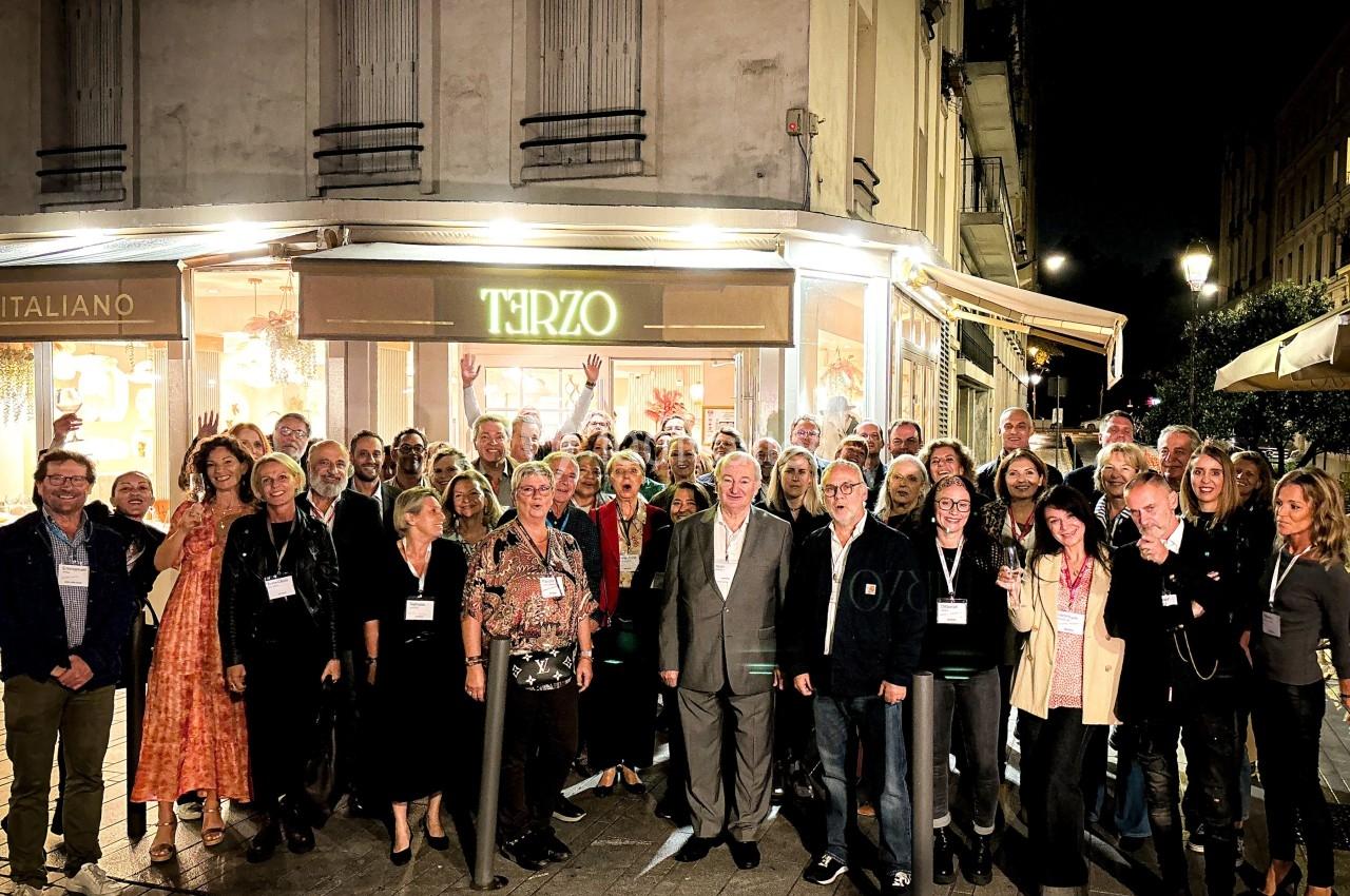Groupe de personnes posant devant un restaurant éclairé la nuit, dans une rue urbaine.