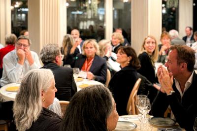 Des personnes assises à des tables dans un restaurant, discutant et partageant un repas dans une ambiance conviviale.