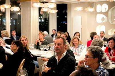Des personnes assises à des tables dans un restaurant, discutant et partageant un repas dans une ambiance conviviale.