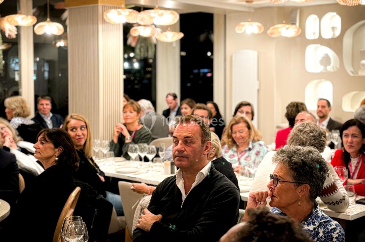Groupe de personnes assises dans un restaurant, attentives à une présentation ou un discours.
