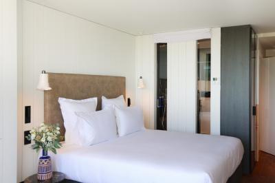 Piscine intérieure avec eau sombre, transats blancs, murs en bois et pierre, et une personne en peignoir flouement visible.