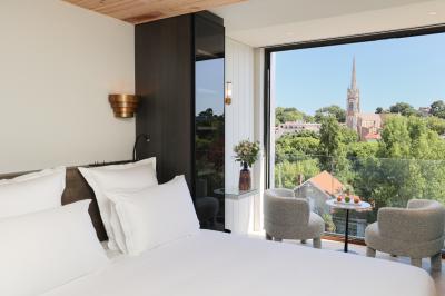 Piscine intérieure avec eau sombre, transats blancs, murs en bois et pierre, et une personne en peignoir flouement visible.
