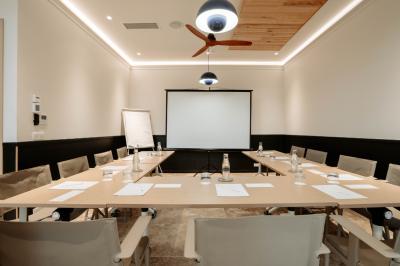 Piscine intérieure avec eau sombre, transats blancs, murs en bois et pierre, et une personne en peignoir flouement visible.