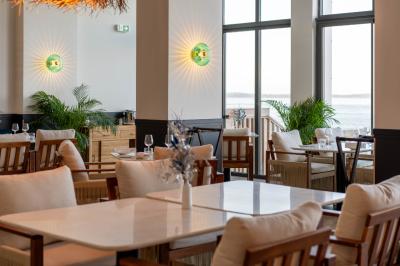 Piscine intérieure avec eau sombre, transats blancs, murs en bois et pierre, et une personne en peignoir flouement visible.