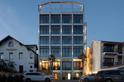 Piscine intérieure avec eau sombre, transats blancs, murs en bois et pierre, et une personne en peignoir flouement visible.