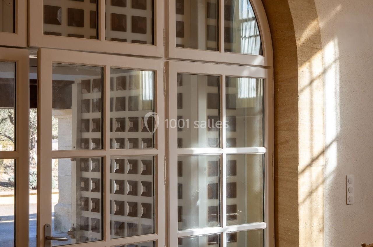 Porte-fenêtre vitrée en bois blanc avec une arche en pierre, laissant entrer la lumière naturelle.