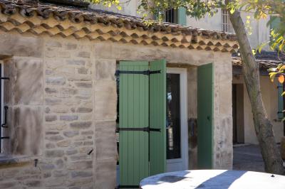 Terrasse couverte en bois avec mobilier d'extérieur blanc, donnant sur un jardin arboré et une allée gravillonnée.