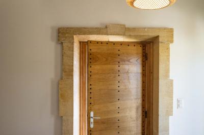 Terrasse couverte en bois avec mobilier d'extérieur blanc, donnant sur un jardin arboré et une allée gravillonnée.