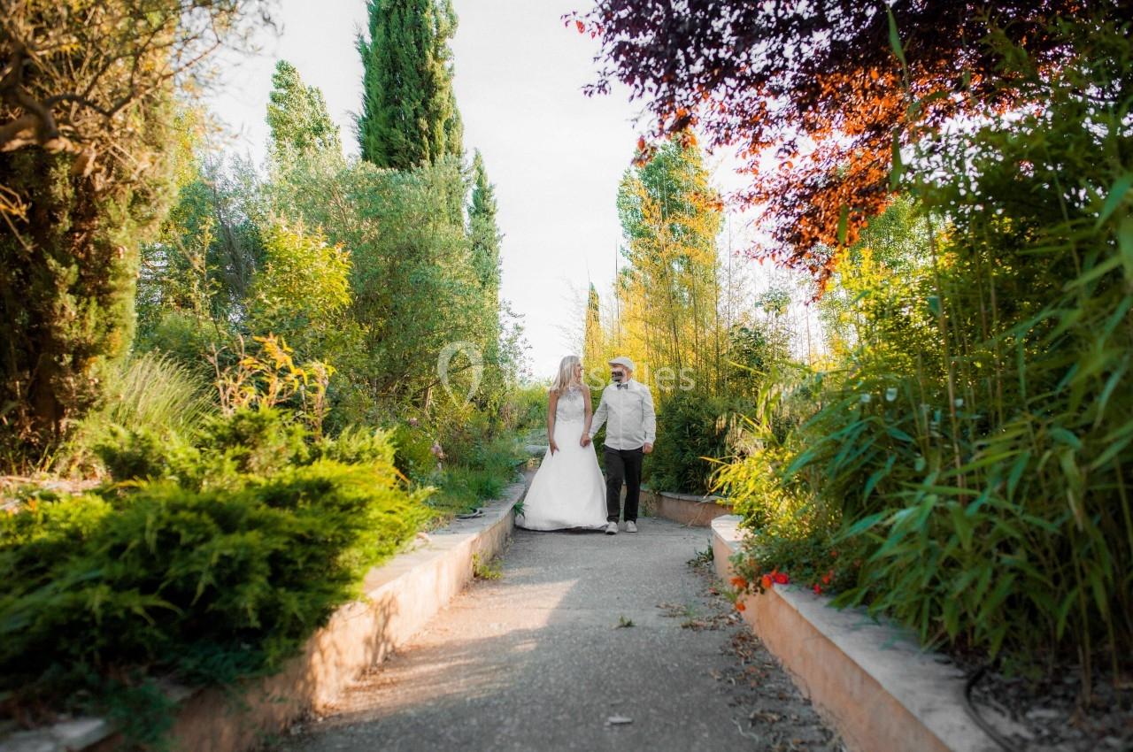 Un couple marche sur un chemin entouré de végétation luxuriante sous une lumière douce.