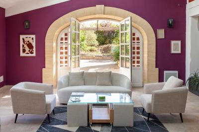 Terrasse couverte en bois avec mobilier d'extérieur blanc, donnant sur un jardin arboré et une allée gravillonnée.