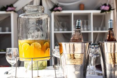 Terrasse couverte en bois avec mobilier d'extérieur blanc, donnant sur un jardin arboré et une allée gravillonnée.