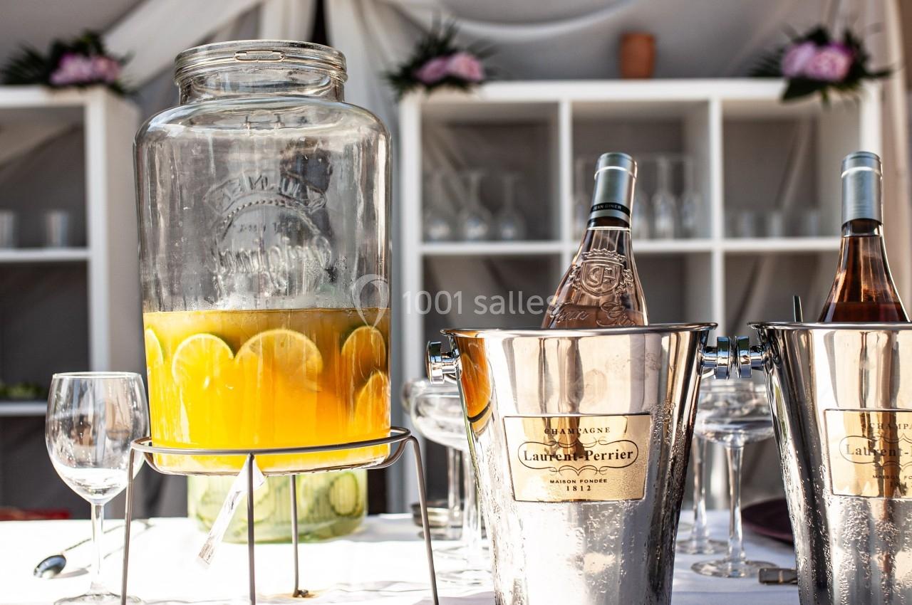 Carafe de jus d'orange avec des tranches de citron et deux seaux à champagne contenant des bouteilles, sur une table dressée.
