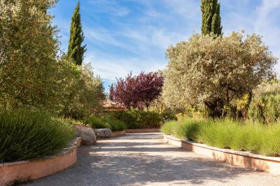 Terrasse couverte en bois avec mobilier d'extérieur blanc, donnant sur un jardin arboré et une allée gravillonnée.