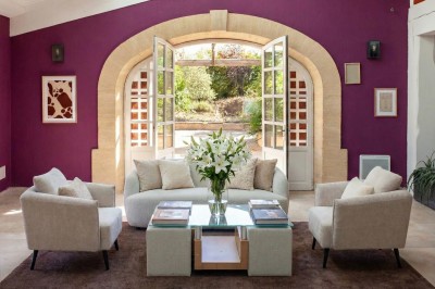 Salle à manger et salon avec table en bois, canapés clairs, lampes suspendues et lumière naturelle.