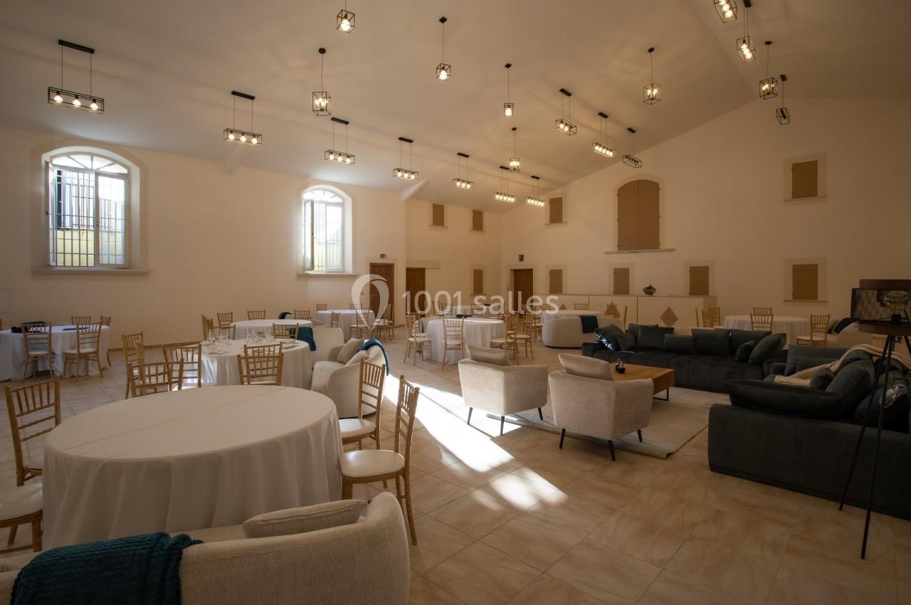 Salle lumineuse aménagée avec des tables rondes, des chaises en bois et des canapés, éclairée par des fenêtres et des…