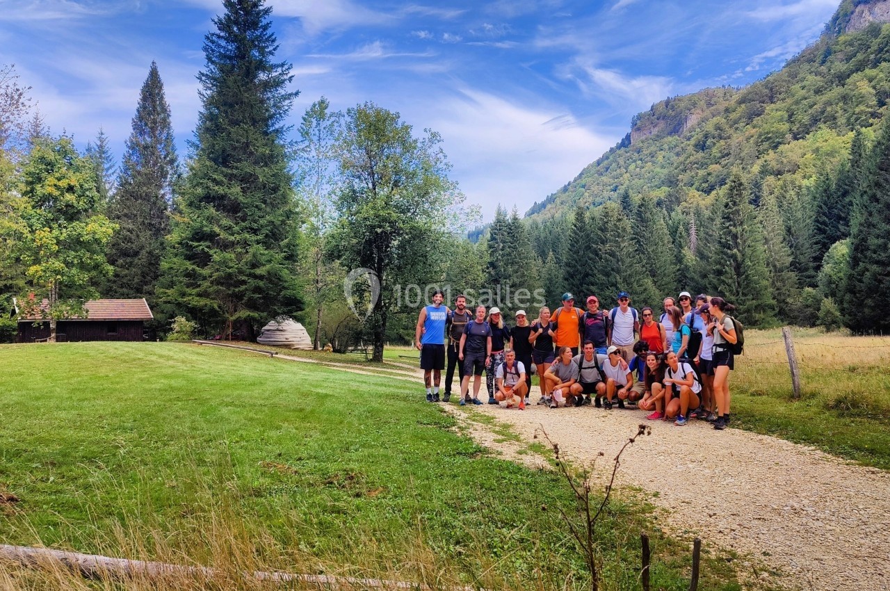 Location salle Crozets (Jura) - Domaine Le Coupet #11 Un groupe de personnes pose sur un chemin en pleine nature, entouré de montagnes, arbres et prairies.