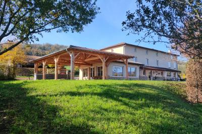Salle à manger avec table en bois, chaises assorties, escalier en bois, et cuisine ouverte dans un intérieur chaleureux.