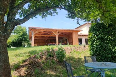 Salle à manger avec table en bois, chaises assorties, escalier en bois, et cuisine ouverte dans un intérieur chaleureux.