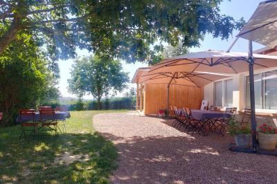 Salle à manger avec table en bois, chaises assorties, escalier en bois, et cuisine ouverte dans un intérieur chaleureux.