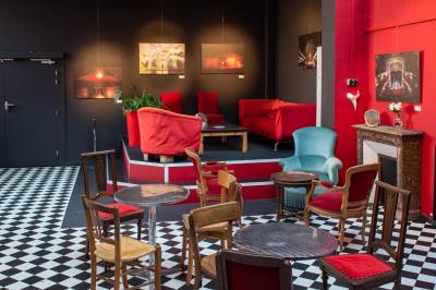 Espace salon avec canapés et fauteuils rouges, table basse en bois, plantes et photos encadrées sur un mur sombre.