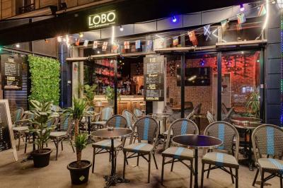 Texte sur un mur en briques indiquant les capacités d'accueil de trois espaces : salle principale, salle au fond, terrasse.