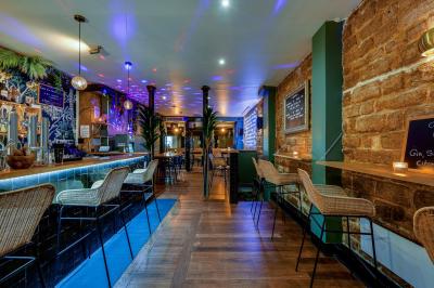 Une rangée de bouteilles de vin variées alignées sur un comptoir en bois, avec un bar en arrière-plan.