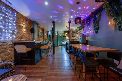 Une rangée de bouteilles de vin variées alignées sur un comptoir en bois, avec un bar en arrière-plan.