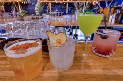 Une rangée de bouteilles de vin variées alignées sur un comptoir en bois, avec un bar en arrière-plan.