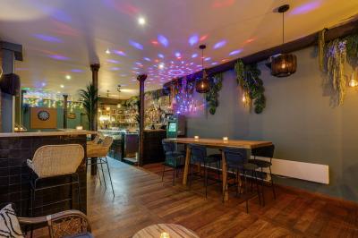 Une rangée de bouteilles de vin variées alignées sur un comptoir en bois, avec un bar en arrière-plan.