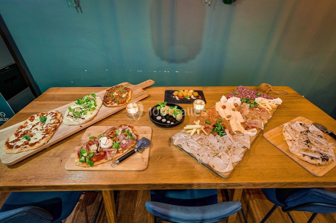 Table en bois garnie de planches de charcuterie, fromages, pains et plats variés, avec bougies décoratives.