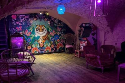 Salle sombre avec un comptoir à gauche, un sol en béton éclairé par des lumières colorées et une sortie illuminée au fond.