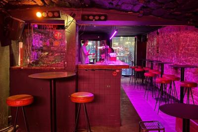 Salle sombre avec un comptoir à gauche, sol en béton et lumières colorées projetées au sol.