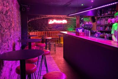 Salle sombre avec un comptoir à gauche, sol en béton et lumières colorées projetées au sol.